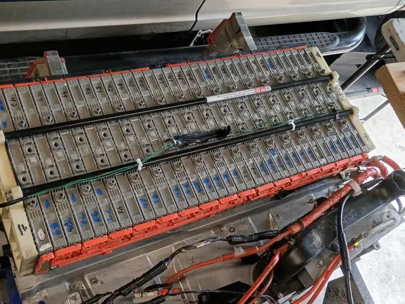 Hybrid battery pack with the cover off, showing rows of cells and bus bars