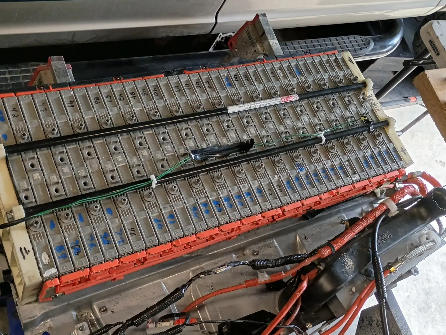 Hybrid battery pack with the cover off, showing rows of cells and bus bars