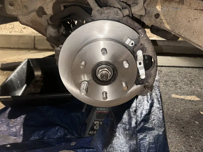 New brake rotor installed on a hub with the car on a jack stand