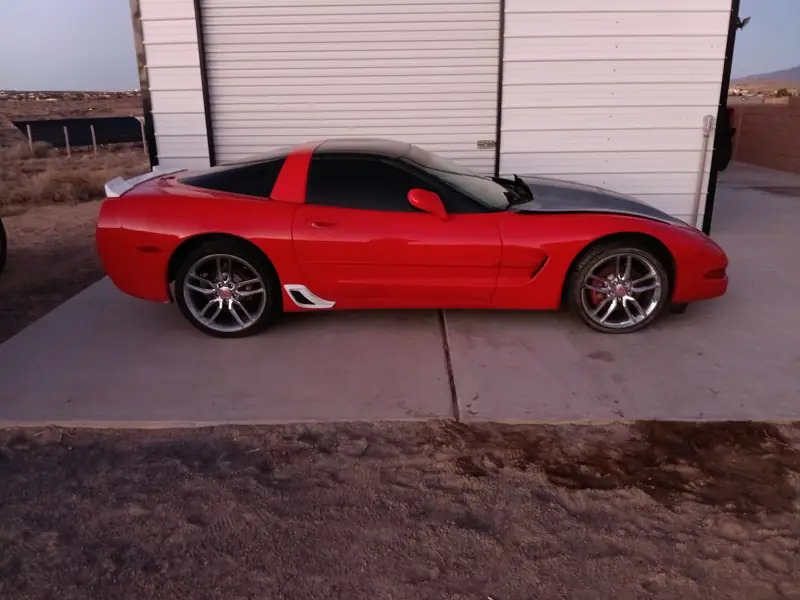 Red C5 Corvette parked on a concrete pad